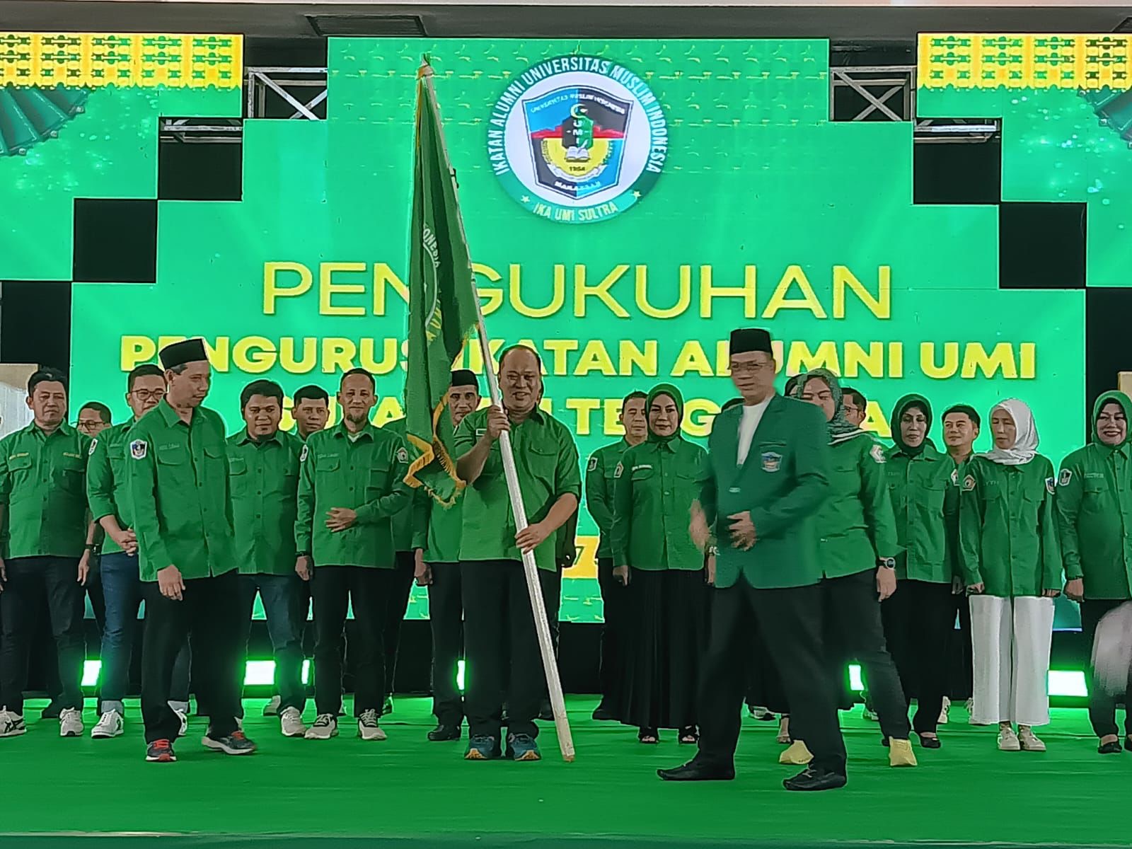 Ruksamin saat menerima bendera pataka pengurus IKA UMI Sultra